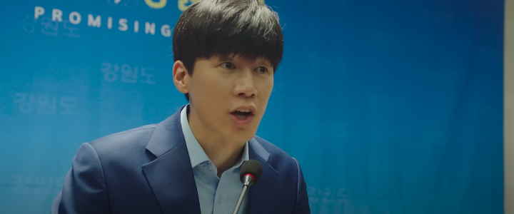 정직한후보2공식예고편스틸컷_김무열이단상에서말을하고있다.