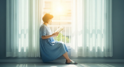 여름 햇살 가득한 창가에서 책을 읽는 중년 여성