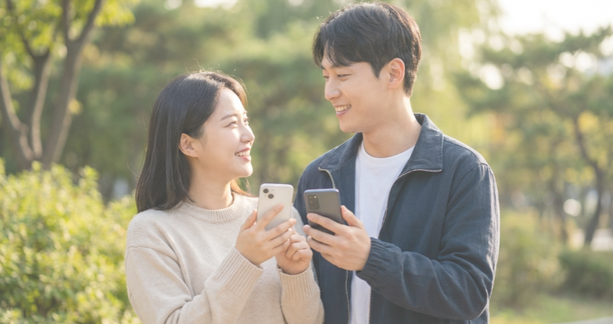 미소 지으며 스마트폰을 보는 행복한 커플