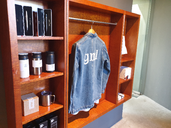 우드 장식장에 텀블러, 볼펜 그리고 의류 및 컵까지 있다. 굿즈 코너