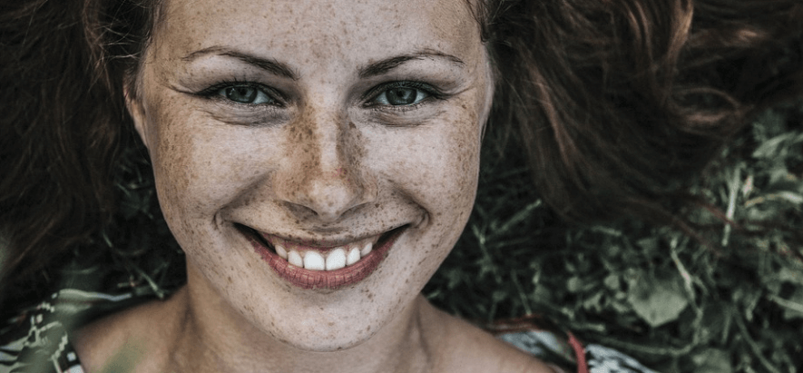 얼굴에 주근깨가 가득한 소녀가 웃고 있다