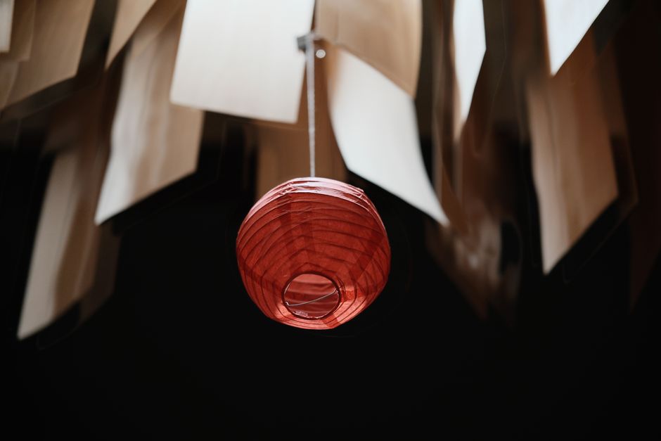 A striking red lantern hanging beneath sheets of paper for a unique decorative effect.