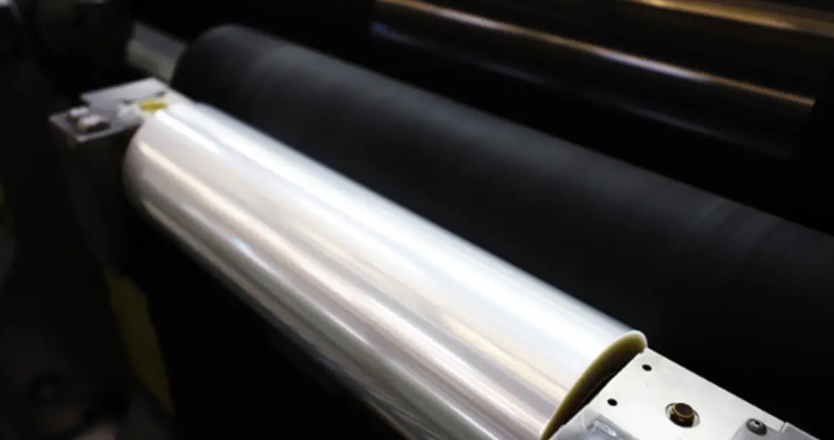 검은 기계 위 긴 은색 원통 필름이 감겨있는 이미지