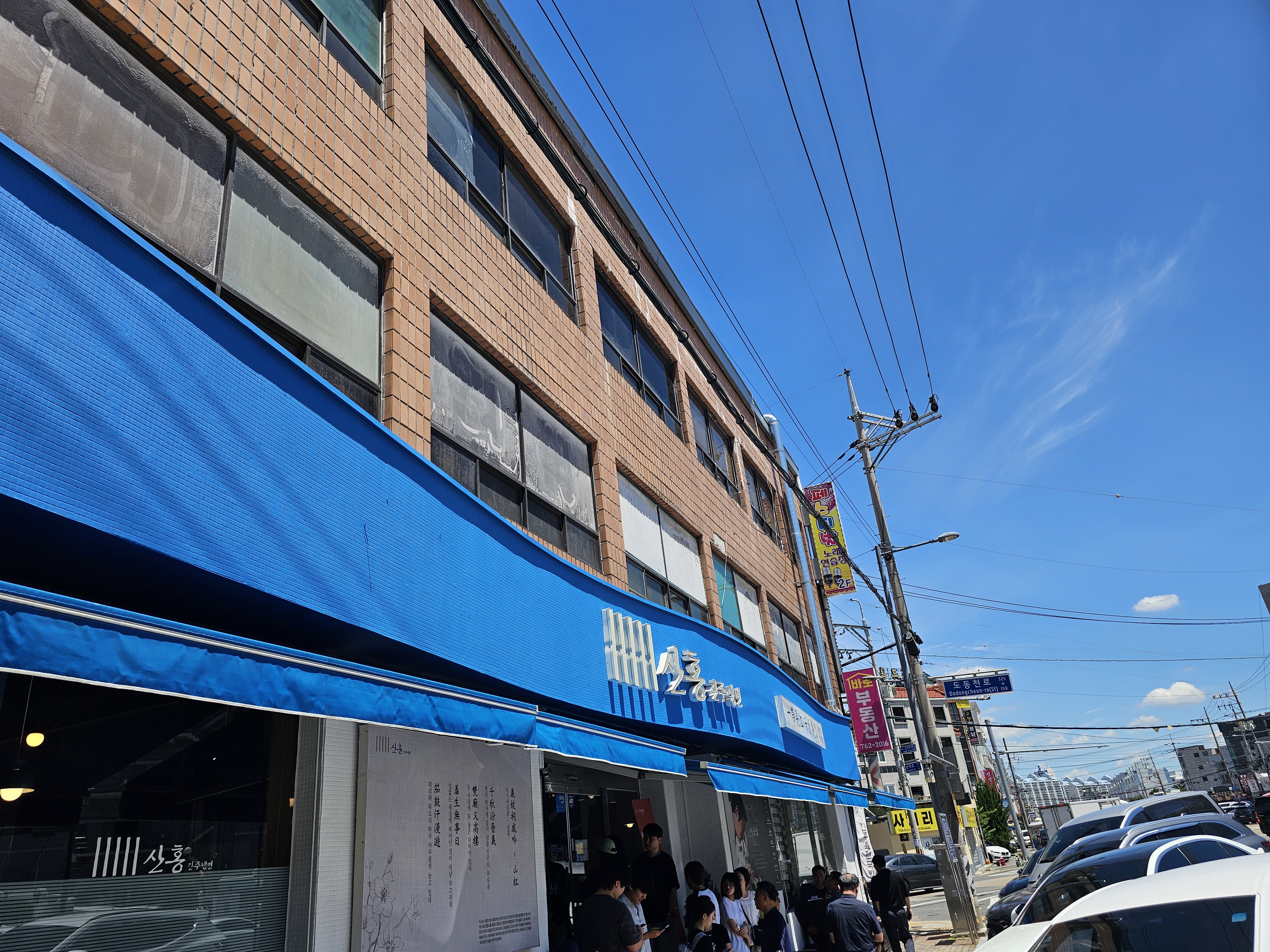 진주냉면 산홍 진주시청점 외관, 파란 천막과 대기줄