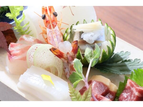 신선한 해산물로 구성된 가이세키 요리의 일부. 회와 새우, 다양한 채소가 섬세하게 장식되어 있는 요리