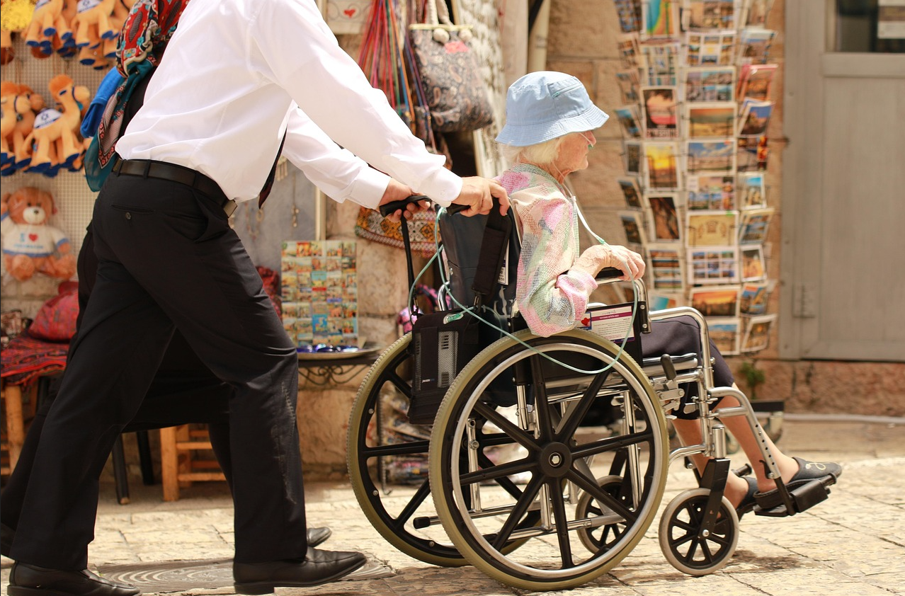 여자어르신 휠체어 밀어주는 사진