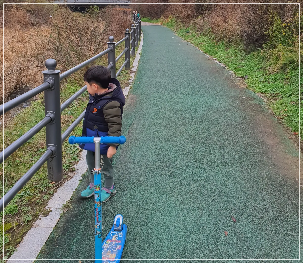 개천옆-산책길에-서있는-어린이-그앞에-파란색-킥보드