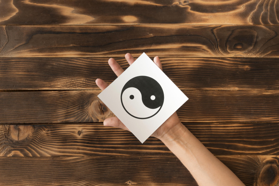 마룻바닥 위에 음양을 나타내는 태극 모양의 그림을 그린 네모난 종이를 왼쪽 손으로 받치고 있는 것을 찍은 사진