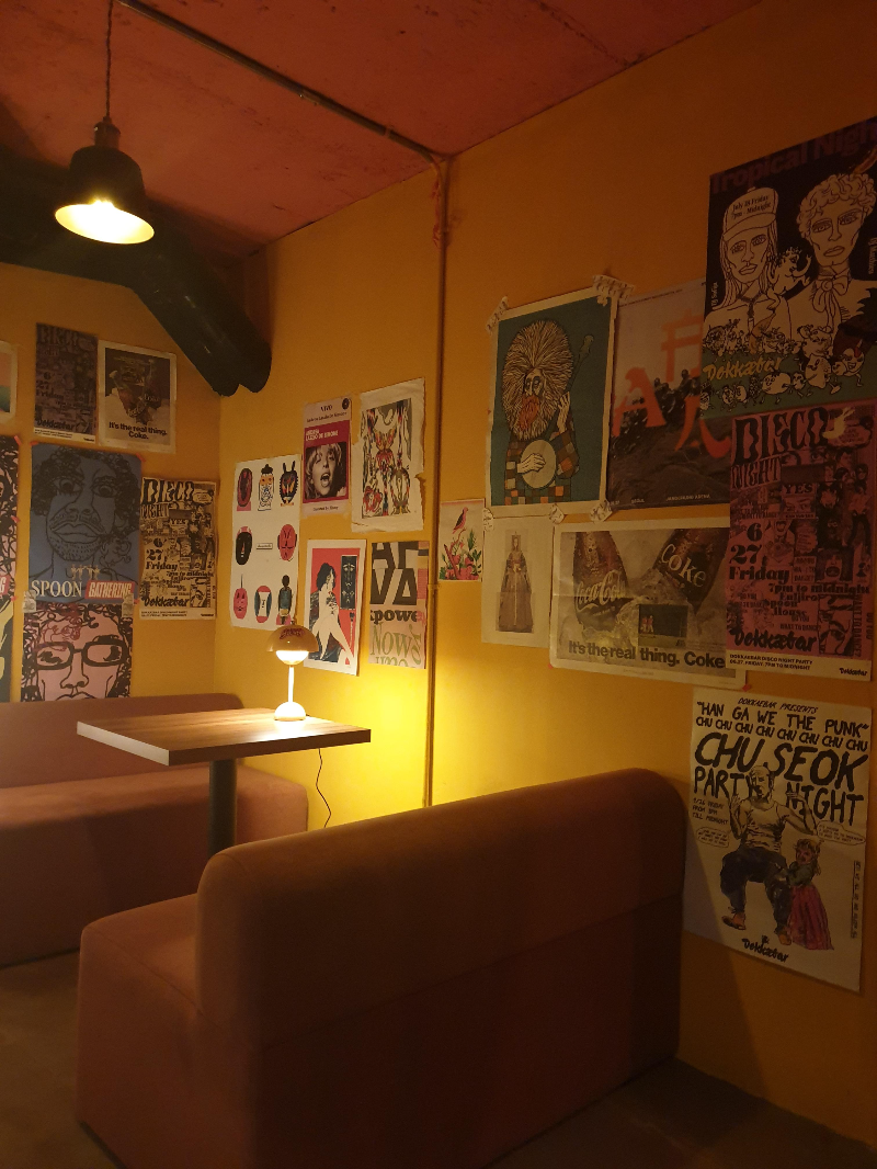 노란색 조닝. 테이블에는 조명이 있고 벽에는 그림과 사진이 가득하다.