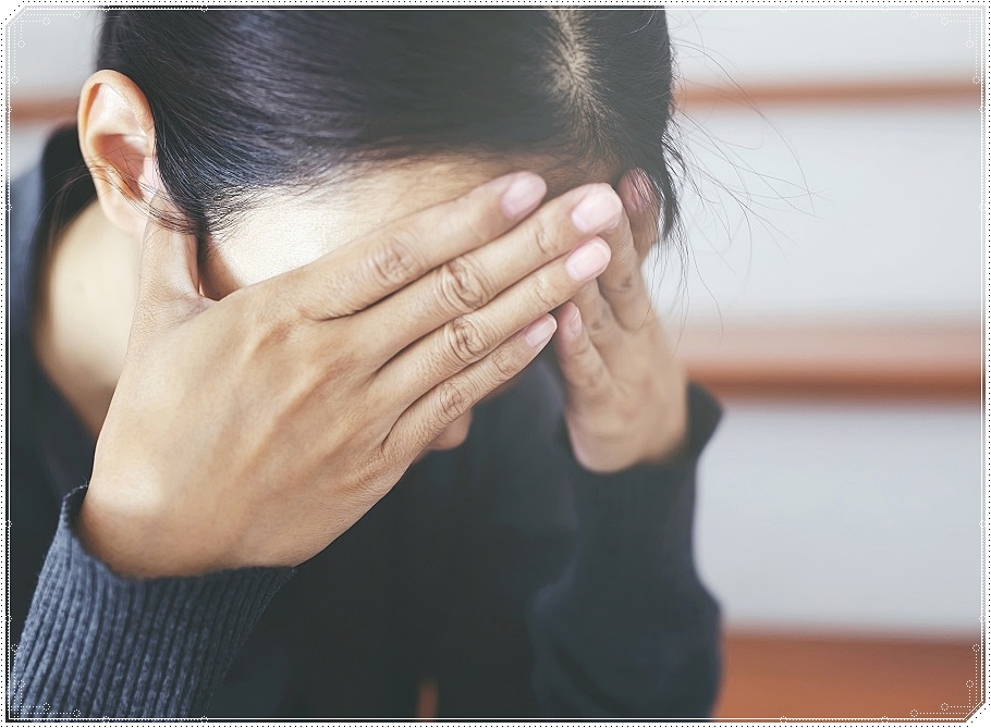 양손으로 얼굴을 가린 채 고개를 숙인 여성의 모습