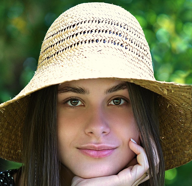 모자를-쓴-여성이-턱을-괴고-웃고-있습니다.