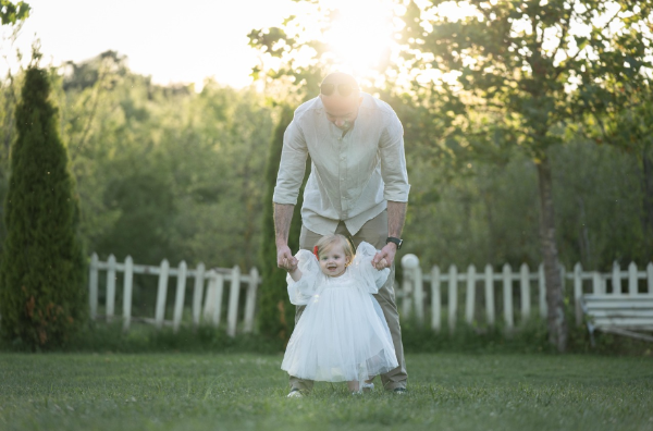 아빠가 사랑스러운 아기의 손을 잡고 정원을 걷는 모습