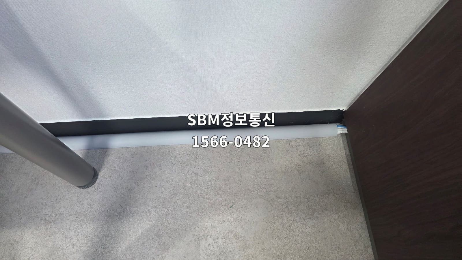 문틀 하단 벽면을 따라 회색 고강도 바닥 몰딩으로 랜선을 깔끔하게 마감한 사무실 현장