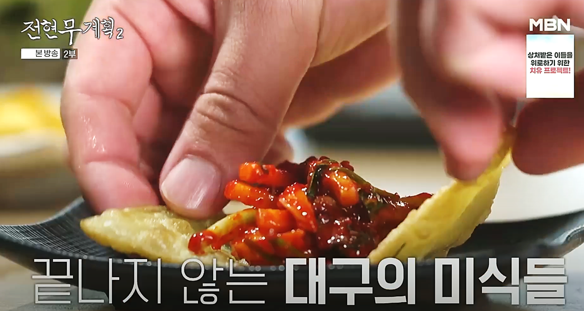 납작만두 위에 무침회를 얹어 싸서 먹는 모습, 전현무계획2 방송 장면