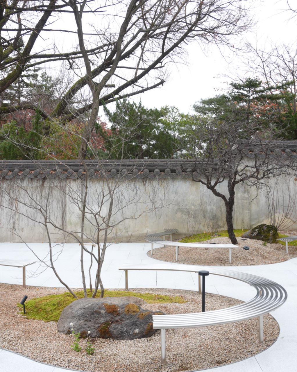 삼청동 포스톤즈 삼청점 야외 정원 공간, 곡선형 벤치와 이끼, 자갈, 고목이 어우러진 감성적인 조경 디자인