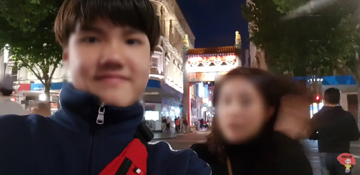 호주 멜버른 차이나타운 거리에서 밤에 찍은 셀카, 전통 문과 불빛이 어우러진 활기찬 분위기