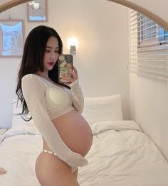 침대위에서-불러오는-배를-잡고-셀카를-찍고있는-임신부