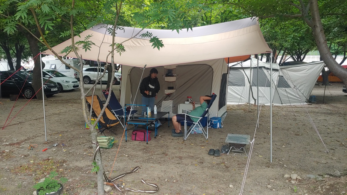 타프 아래 의자에 앉아 휴식을 취하는 가족들