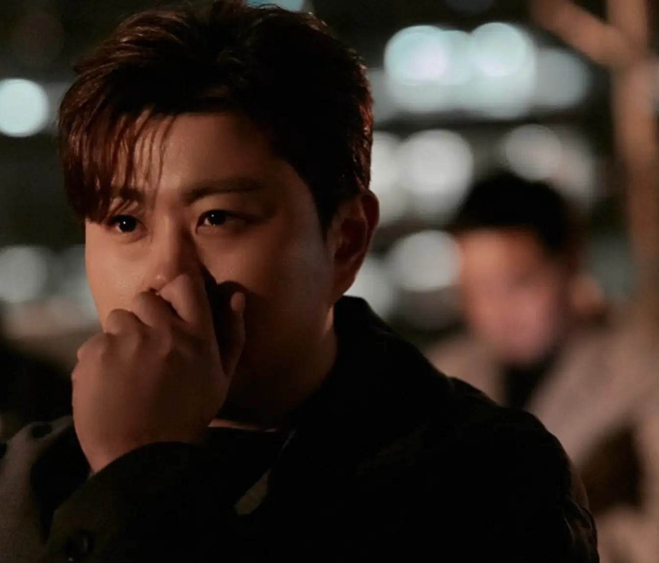 어두운 밤 검은옷을 입은 김호중이 왼손으로 턱을 괴고 있는 모습