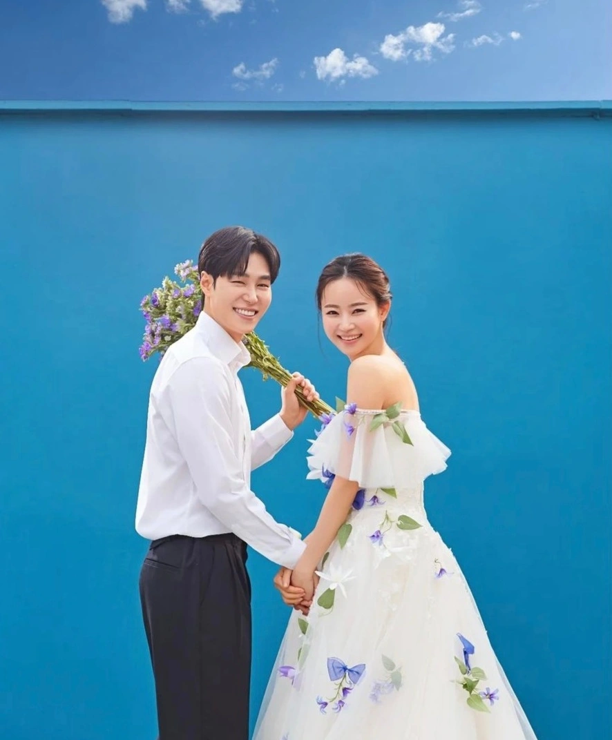 파란벽-위에-파란-하늘이-있고-그앞에-신랑-신부가-손잡고있는-웨딩사진