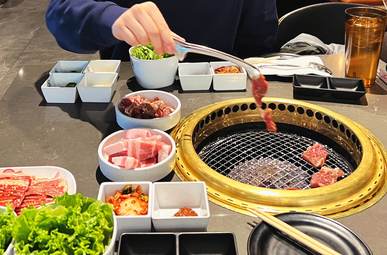 Korean-style BBQ table setup with kimchi, ssamjang, lettuce wraps, and pickled radish