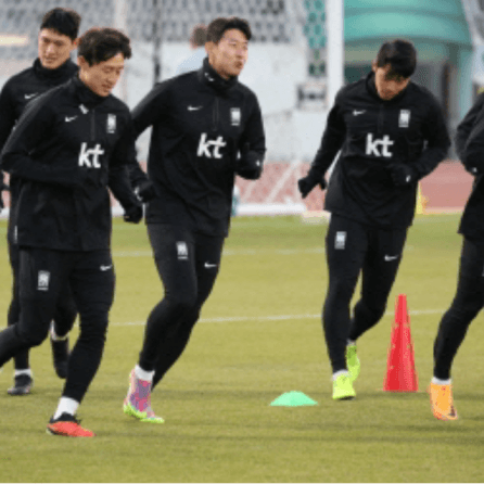 검은 트레킹복을 입고 축구장을 달리고 있는 선수들