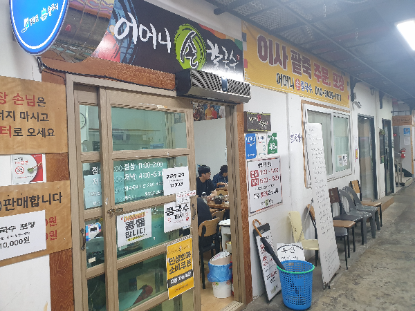 미로 중앙시장 2층 복도와 어머니 손 칼국수 입구. 문에 여러 pop가 붙어있다.