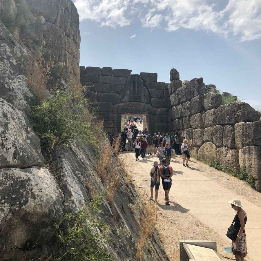 미케네 사자의 문 앞, 큼직한 돌로 쌓인 성벽 사이로 많은 관광객이 오가고 있는 풍경.