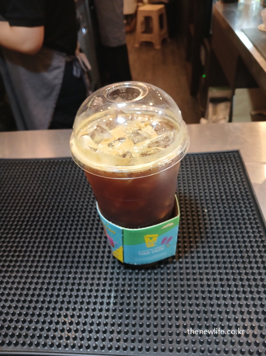 아침 공복에 마시는 아이스 아메리카노 실사 컵 사진, 빈속 커피 습관이 건강에 미칠 수 있는 위험을 상징적으로 보여줌