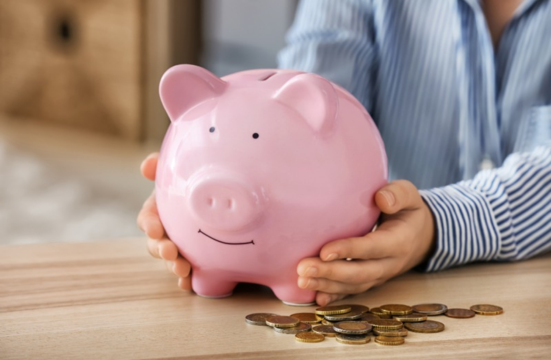 핑크색 돼지 저금통을 한 남자가 잡고 있다.