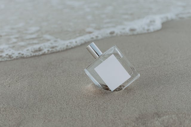 모래사장 위에 놓인 미니멀 향수병 이미지, 은은하게 남는 향수를 표현한 썸네일