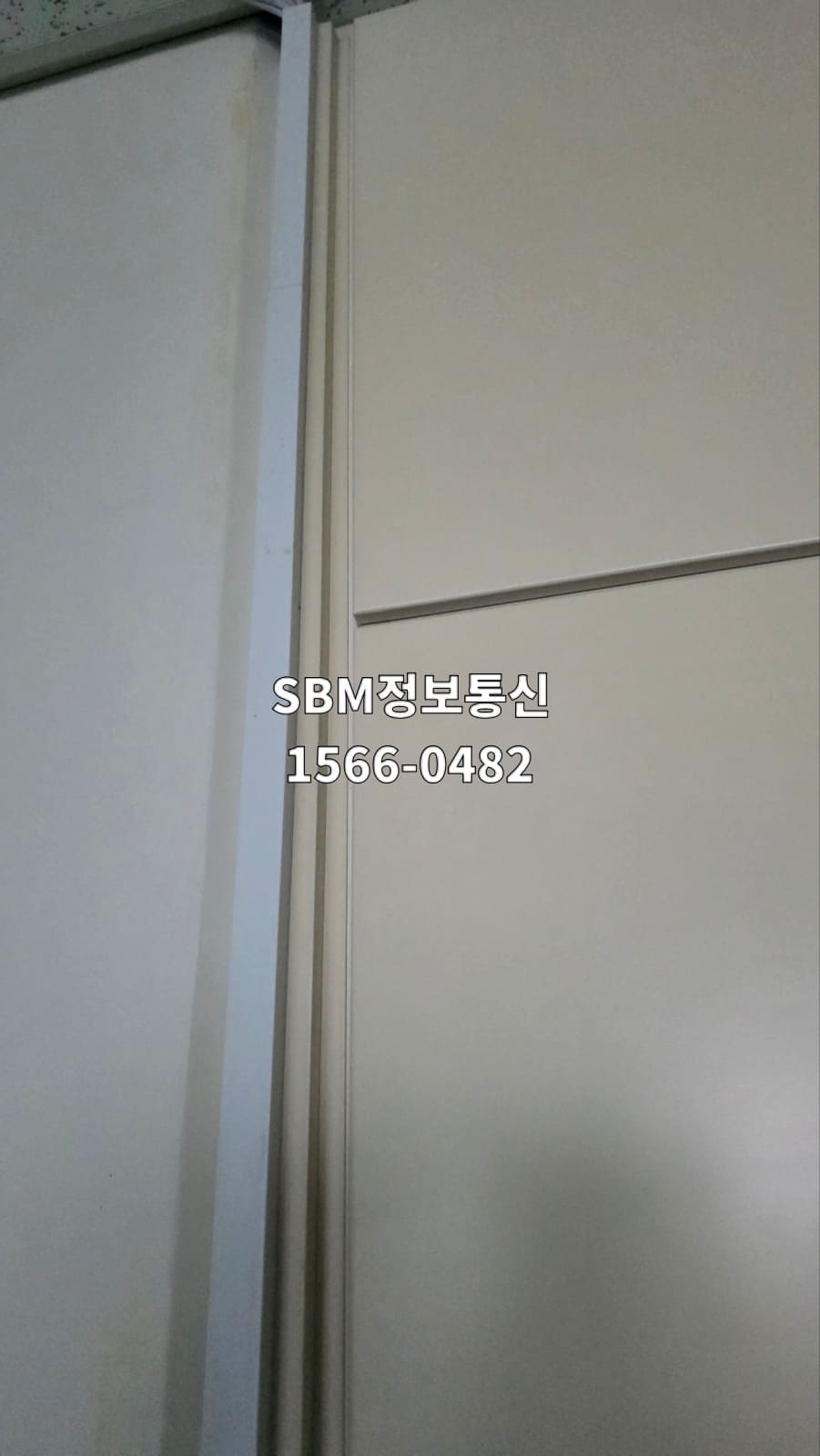 사무실 벽면 구석을 타고 수직으로 내려오는 선을 덮은 사각 기둥 형태의 하얀색 몰딩