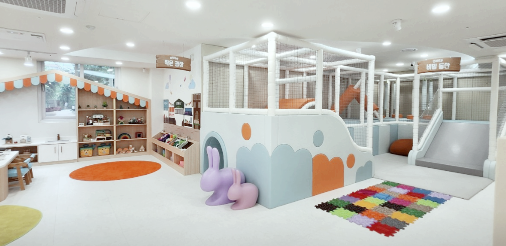 깔끔한 실내 키즈카페에 토끼인형과 각종 아이들 장난감이 보인다