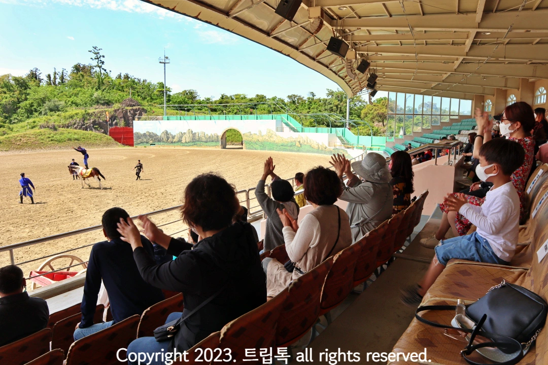 말 위에서 줄넘기를 하는 모습을 보고 관객들이 환호한다.