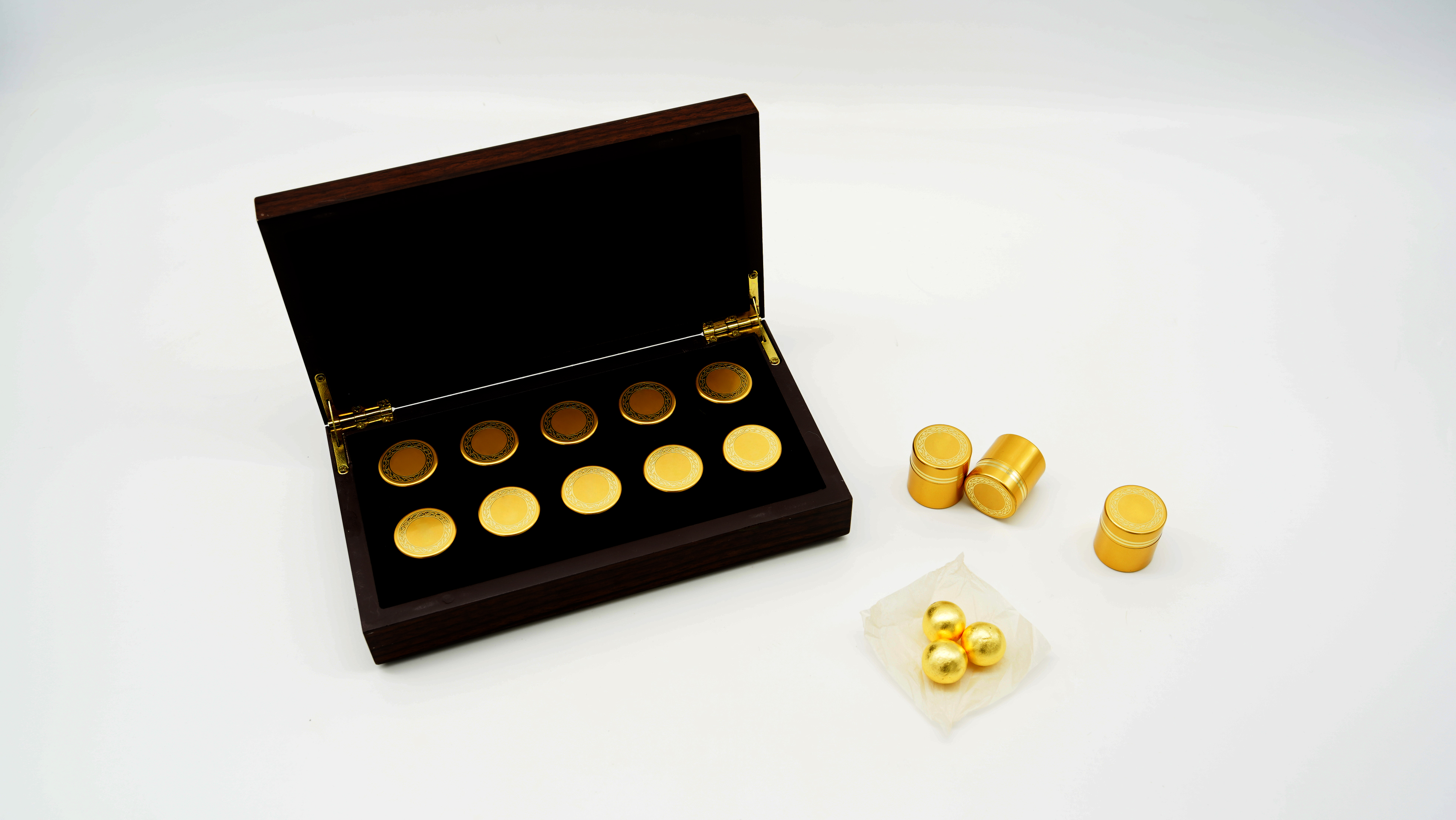 고급진 오크색의 나무 상자에 금색 우황청심원이 들어 있는 금색 환병이 10개가 꼽혀 있고&#44; 바닥에는 금색의 우황청심원 환병 3개가 놓여 있고&#44; 그 앞에는 작은 종이 위에 우황청심원 3개가 놓여 있는 사진