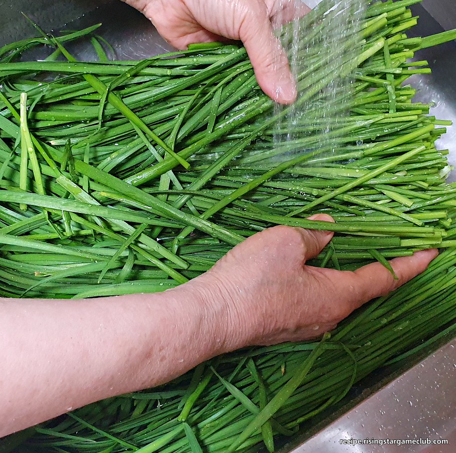 부추 겉절이를 만들기 위해 부추를 흐르는 물에 씻는 사진