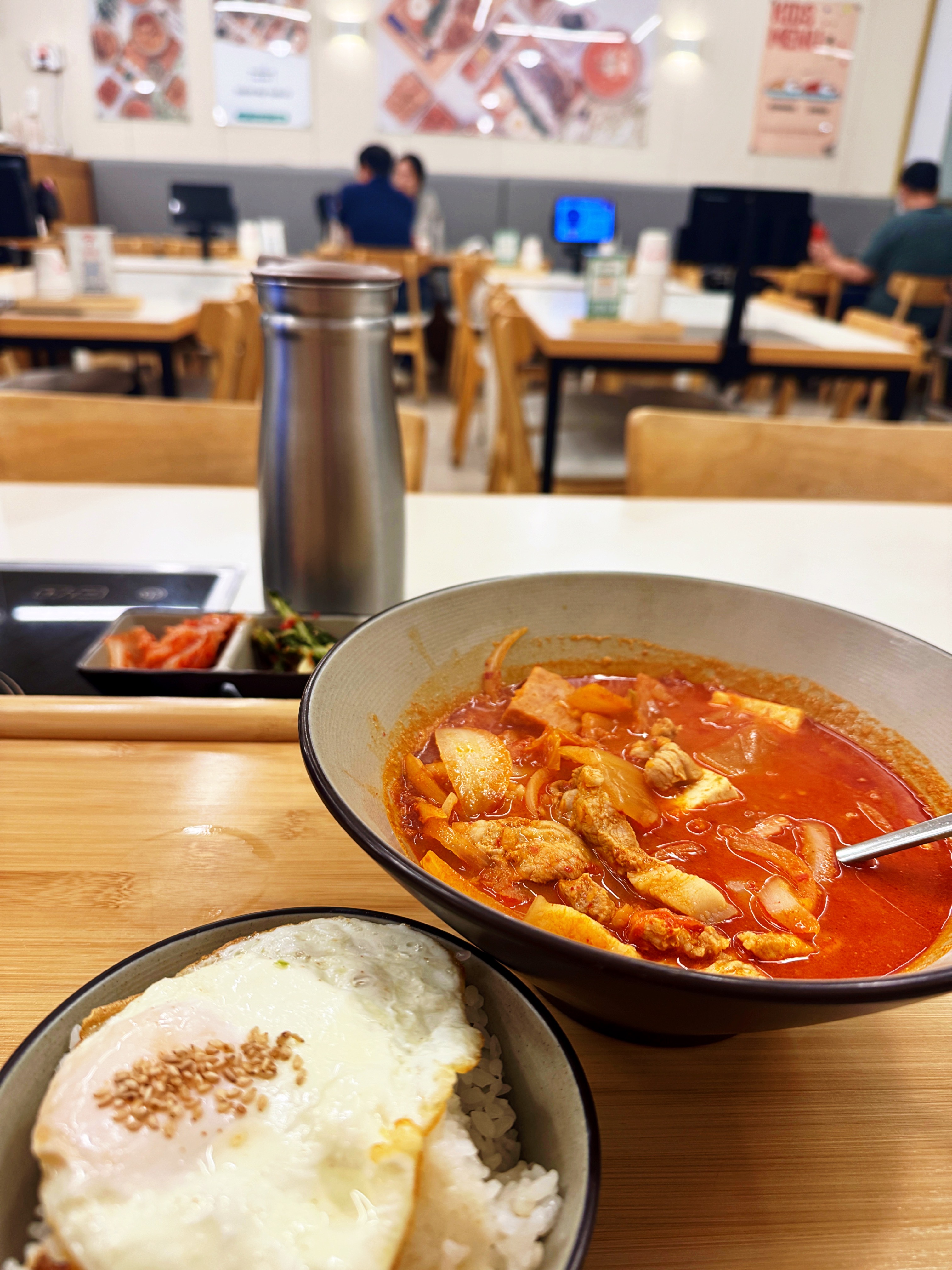 용인 수지구 동천동 바른식탁 김치찌개. 큼직한 그릇에 김치와 두부&amp;#44; 고기&amp;#44; 스팸이 푸짐하게 들어 있고&amp;#44; 옆에는 계란프라이가 얹힌 밥이 함께 담겨 있다. 뒤쪽으로는 기본 반찬과 매장 내부가 보인다.