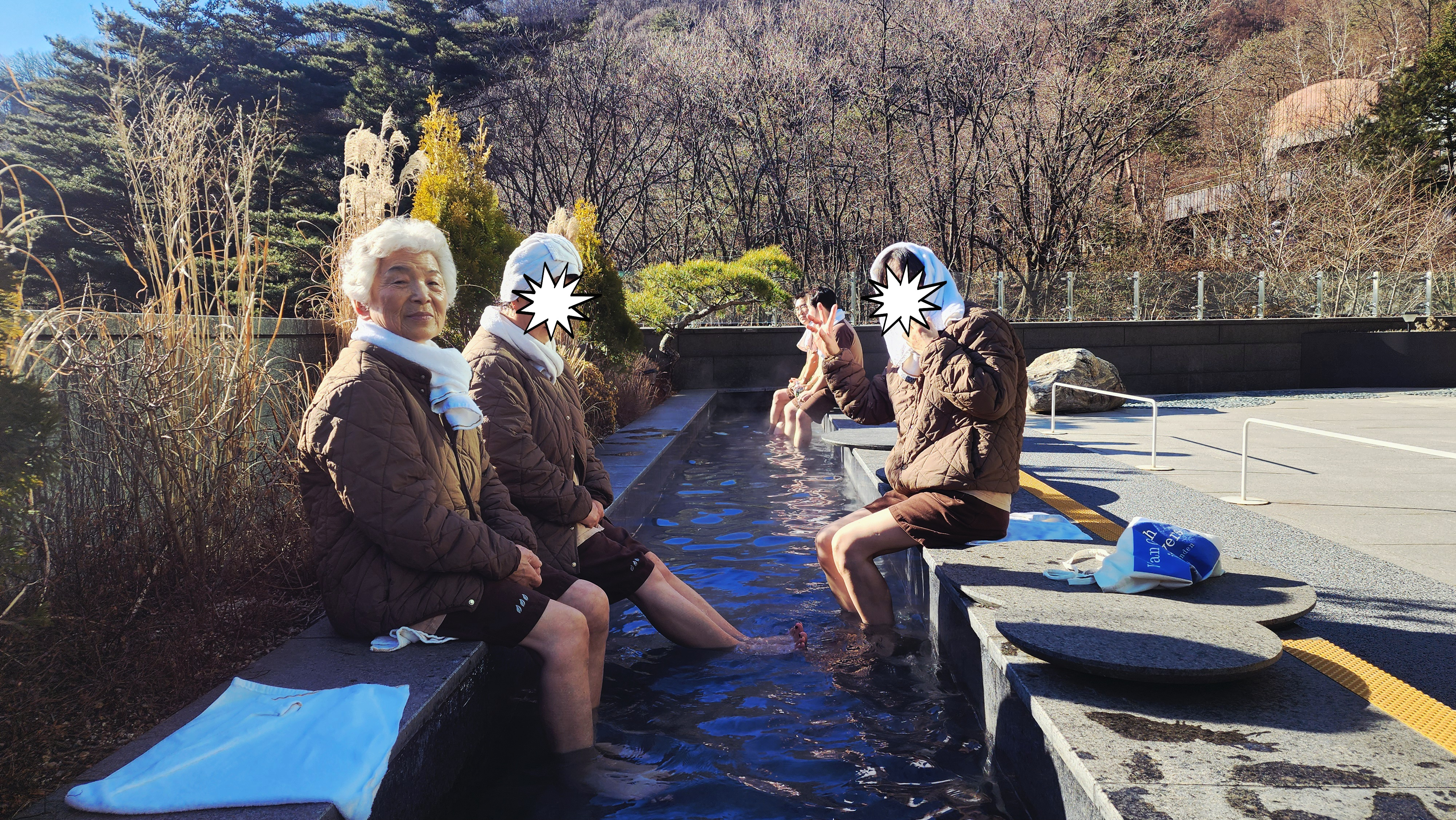 겨울 야외 족욕탕에서 나란히 앉아 발을 담그고 있는 가족들의 모습