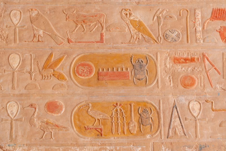 Close-up of ancient Egyptian hieroglyphs carved into a stone wall, showcasing historic symbols.