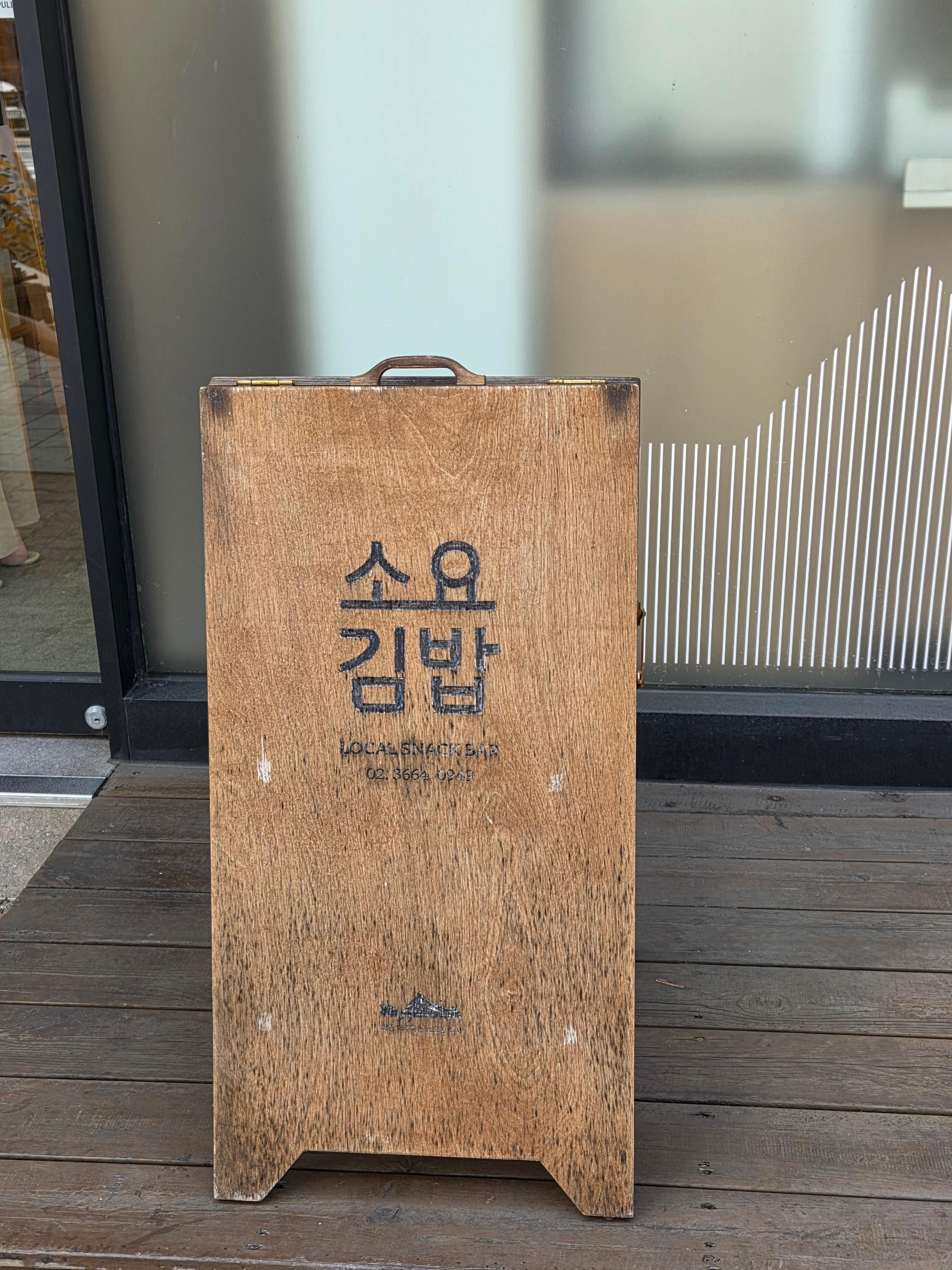 소요김밥 매장 앞, 나무 재질의 소요김밥 입간판 전경.