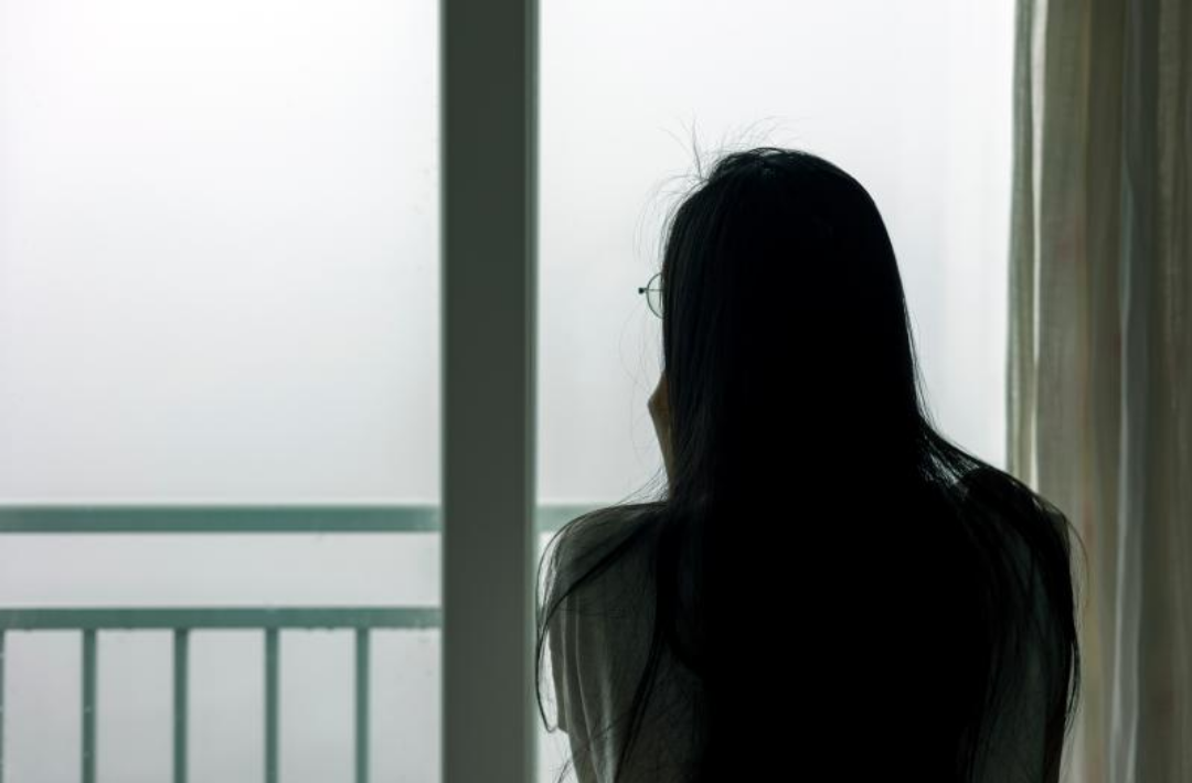 한 여성이 안개낀 밖을 쳐다보고 있다.