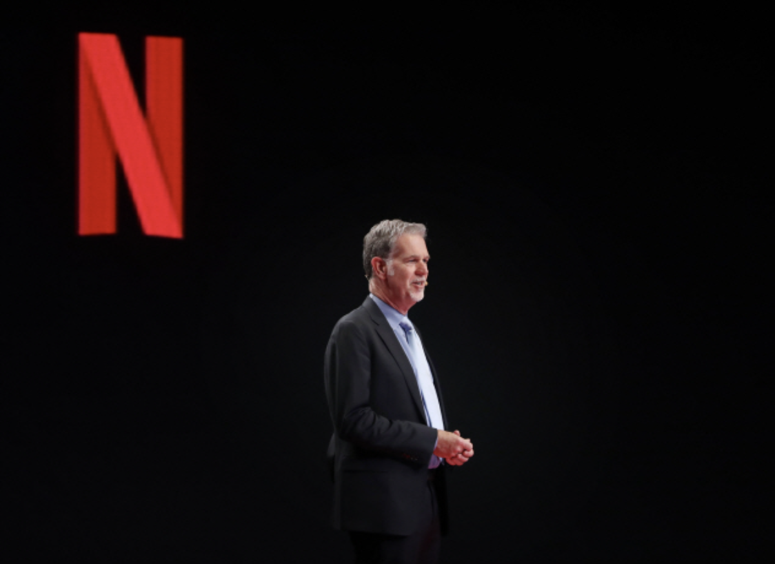 플릭스-로고-앞에서-기조-연설을-하는-리드-헤이스팅스-스트리밍-서비스-디지털-혁신과-미디어-리더십을-상징하는-이미지