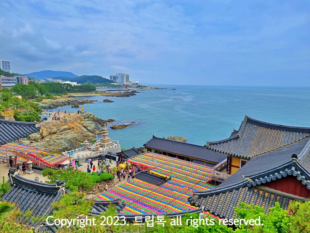 파란 하늘 아래 파란 바라가 있고 그 아래 용궁사를 내려다본 풍경이다. 알록달록한 연들이 줄지어 빠곡히 달려있다.