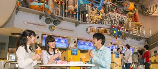 여자 2명과 남자 한명이 테이블에 앉아서 음료수를 한손에 들고 웃고 있다.