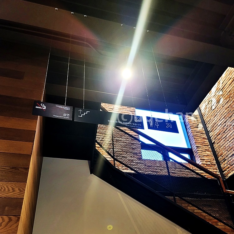 동두천 스타벅스내에서 금연이라는 안내와 2층으로 올라가는 계단 및 화장실 안내가 되어있는 표지판 사진이다.