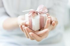 반지가-담긴-하냔-상자를-분홍빛-리본으로-묶고-두손을-하트로-만들어-주는-모습