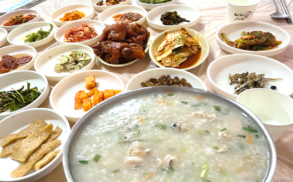 백합이 가득 들어 있는 뽀얀 백합죽과 족발 20여 가지 반찬이 가득 차려진 백합죽 한 상