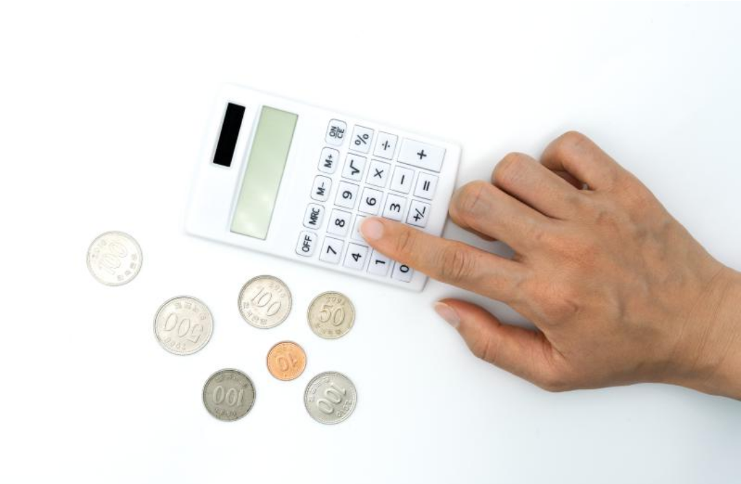 한 사람이 널린 동전 사이로 계산기를 두드리고 있다.