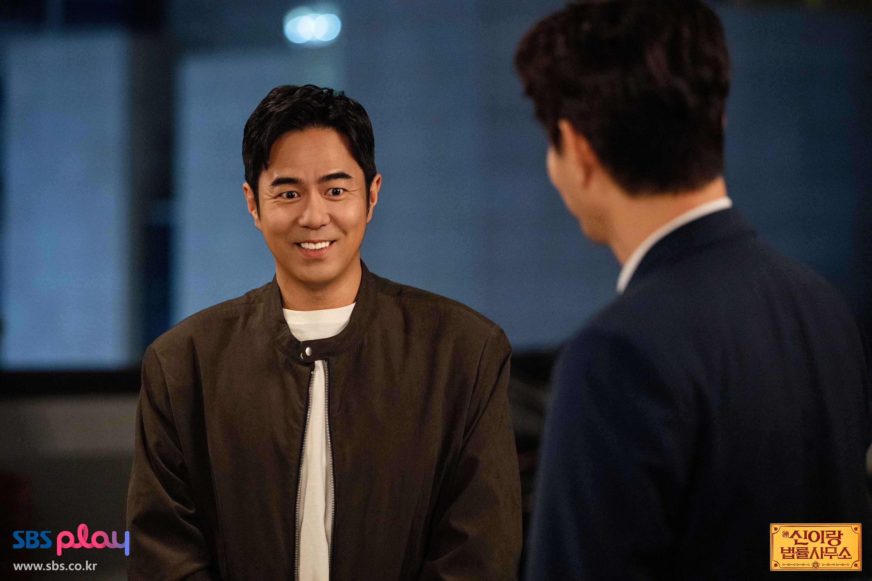 신이랑 법률사무소 최종회 공식 스틸에서 갈색 재킷을 입은 남성이 밝게 웃는 장면