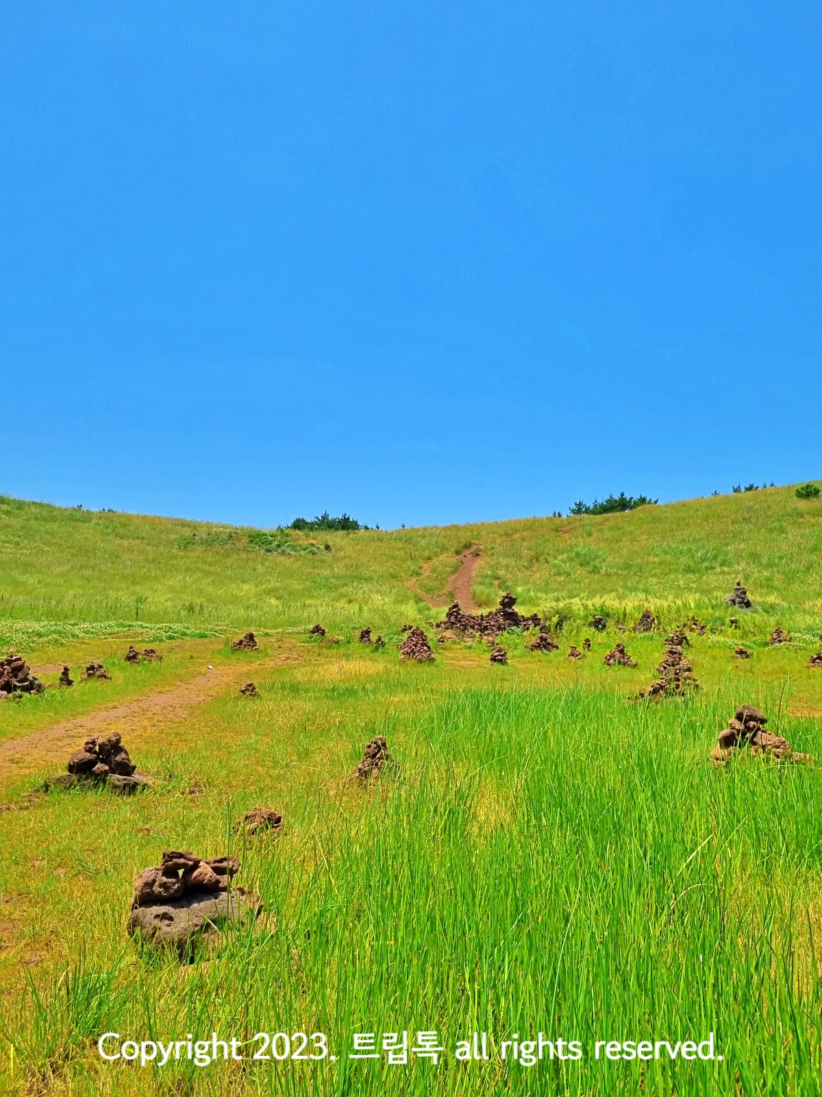 파람 하늘아해 연두색 풀등리 자라고 돌탑들이 여기저기 쌓여있다
